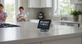 Smart display on a countertop in a modern kitchen shows various apps on its screen. Royalty Free Stock Photo