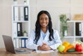 Smart eating and healthy nutrition. Portrait of positive black dietitian looking at camera and smiling at workplace