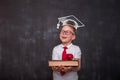 Smart educated school kid student with graduation hat doodle picture on chalkboard. little boy with paintbrush creative Royalty Free Stock Photo