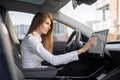 Smart electric car concept. Pretty woman in formal wear, controlling modern electric self-steering car with a digital