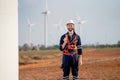 Smart engineer or technician man stand with holding light bulb and look at camera with background of windmill or wind turbine and Royalty Free Stock Photo