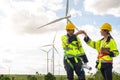 Smart engineers with protective helmet giving fist bump at electrical turbines field