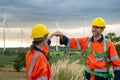 Smart engineers with protective helmet giving fist bump at electrical turbines field