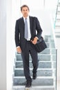 Smart executive carrying an office bag. Full length of a smart business man walking down the stairs with an office bag. Royalty Free Stock Photo