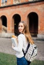 Smart female college student with bag and books on campus outdoors