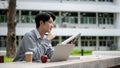 A smart and focused Asian male university student is reading a book in a campus park Royalty Free Stock Photo