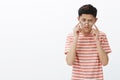 Smart and focused handsome young male asian student trying solve tough puzzle taking off glasses, frowning while Royalty Free Stock Photo