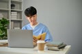 A smart and focused young Asian male medical student in scrubs reading a book at his desk Royalty Free Stock Photo