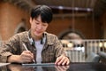 Smart and focused young Asian man using his digital tablet, remote working at the coffee shop Royalty Free Stock Photo