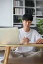 A smart and focused young Asian man is working from home, managing his work Royalty Free Stock Photo