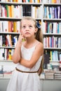 Smart girl child bemused a lot of books in a bookstore