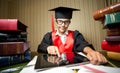 Smart girl in graduation cap using digital tablet at library Royalty Free Stock Photo