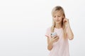 Smart girl knows everything about gadgets. Portrait of cute beautiful blond young child, wearing earphones and picking