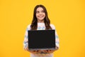 Smart girl with laptop in casual clothes isolated over yellow background. Screen of laptop computer with copyspace