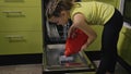 Smart girl learning to use dishwasher. Stylish modern Built In Kitchen Appliances in green black. Child is putting dirty