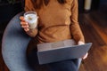 A smart girl siting and working in the office with a laptop and a cup of aromatic espresso  cappuccino. Holding a laptop on her Royalty Free Stock Photo