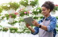 Smart greenhouse with digital control. Smiling african american girl with tablet in hands