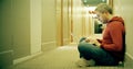 Smart grey haired man in casual clothes uses his laptop in the hotel hallway Royalty Free Stock Photo