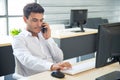 Smart and happy business man using smartphone while working with computer in the modern office