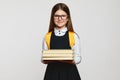 Smart happy school girl in glasses smiling for camera and carrying stack of books Royalty Free Stock Photo