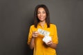 Smart happy successful black woman putting in piggy bank one hundred dollars banknote Royalty Free Stock Photo