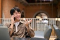 Smart Asian male freelancer or college student on the phone with someone in the coffee shop Royalty Free Stock Photo