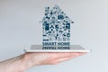 Smart home automation concept. Background with hand holding smart phone and floating text and icons.