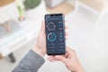 Smart home control app for mobile devices in woman hand. Living room interior in background Royalty Free Stock Photo