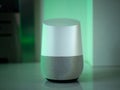 Smart home speaker assistant device in home setting with coloured LED mood lighting - green