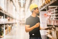 Smart Indian engineer man worker doing stocktaking of product management in cardboard box on shelves in warehouse. Royalty Free Stock Photo