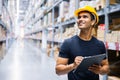 Smart Indian engineer man worker wearing safety helmet doing stocktaking of product management in cardboard box on shelves Royalty Free Stock Photo