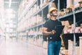 Smart Indian engineer man worker wearing safety helmet doing stocktaking of product management in cardboard box