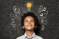 Smart kid with lightbulb. Brainstorming and idea concept. Little cute student boy on chalkboard background Royalty Free Stock Photo