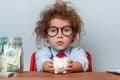 Smart kid putting coin in piggy bank. Child girl in glasses with piggy bank. Money and education Royalty Free Stock Photo