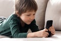 Smart little boy have fun watching video on cellphone gadget Royalty Free Stock Photo