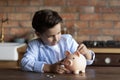 Smart little boy saving money in piggybank