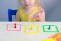 Smart little child, girl 2 years plays with educational toy, learns colors, builds houses from counting sticks, concept childhood