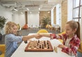 Smart little children, boy and girl shaking hands after match, playing board game, sitting together at the table in Royalty Free Stock Photo