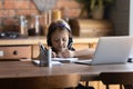 Smart little girl in headphones study online on laptop