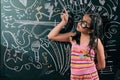 Smart little girl smiling in front of a blackboard Royalty Free Stock Photo