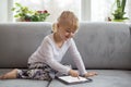Smart little girl using tablet computer while sitting on couch in living room at home Royalty Free Stock Photo