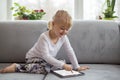 Smart little girl using tablet computer while sitting on couch in living room at home