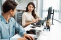 Smart manager talking to woman coworker while typing on laptop. Postulate. Royalty Free Stock Photo