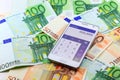 Smart mobile phone open calculator application with euro banknotes on background.