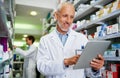 Smart pharmacists use smart technology. a mature pharmacist using a digital tablet in a pharmacy.