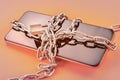 Smart phone in chain with lock on orange background with selective focus