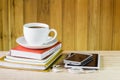 Smart phone,coffee cup,and stack of book on wooden table Royalty Free Stock Photo