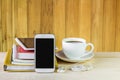 Smart phone, coffee cup, and stack of book on wooden table Royalty Free Stock Photo