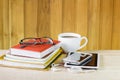 Smart phone,coffee cup,and stack of book on wooden table Royalty Free Stock Photo