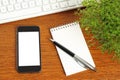 Smart phone, keyboard, notepad, pen and green plant Royalty Free Stock Photo